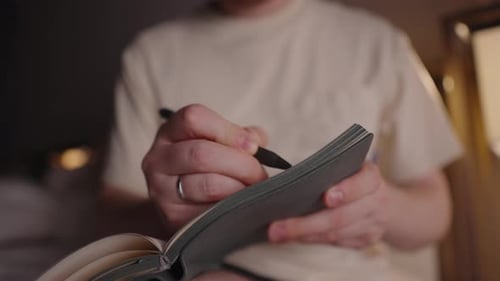 Man Writing in a Notebook with a Pen