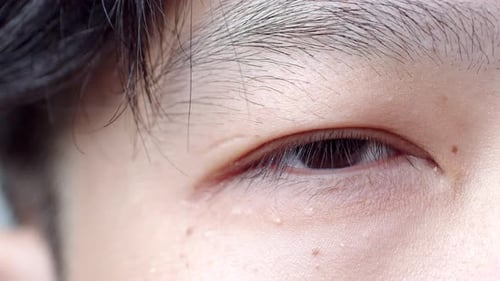Close up of Asian Man's face. Attractive boy with beautiful eyes. Caucasian young male model with ey