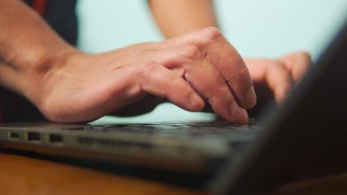 Close Up of Professional Hands Typing on Laptop Keyboard at Wooden Desk