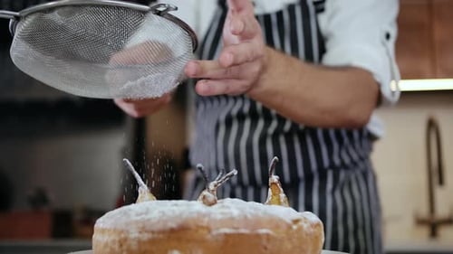 Chef dusts cake with powdered sugar