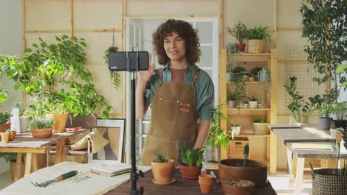 Woman Filming Gardening Tutorial in Greenhouse Setting