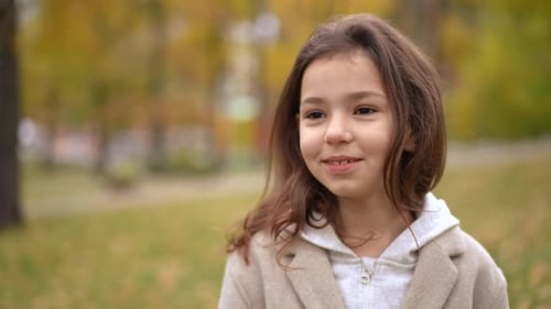 Charming Caucasian Pretty Girl Looking Away and Looking at Camera Standing on Autumn Meadow in Park
