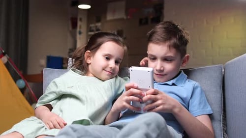 Children Playing Video Game Together on Couch