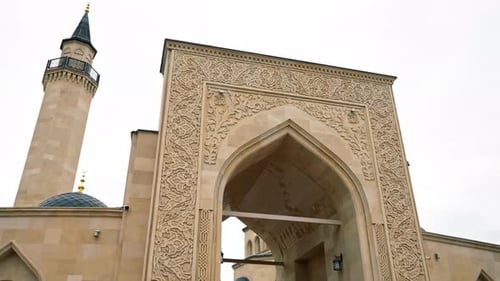 Beautiful cosy entrance to a Muslim mosque surrounded by an arch with Islamic ornaments against sky