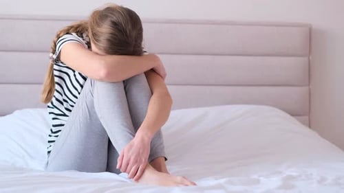 Sad Girl Sitting On Bed Hugging Knees