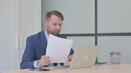 Man Reviews Documents in Bright Office