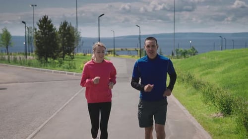 Sports Couple on a Daily Run in the City Park Bright Summer Day and Landscaped Park Area Convenient