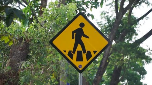 Placa de
passagem para pedestres com folhas de árvores verdes exuberantes no fundo. Sinal de trânsito da Indonésia. Grite