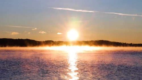4k medium close up Sunrise over a lake with Mountain in the background, sun-ray sprinkling through w