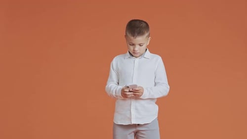 Boy Using Smartphone Against Orange Background
