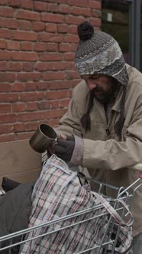 Man Outdoors Adding Liquid to Cup By Shopping Cart