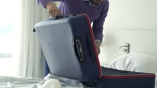 Man Packing Suitcase On Hotel Bed