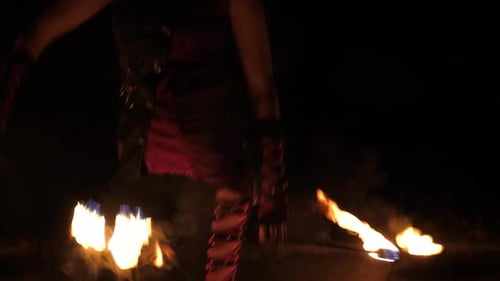 Gros plan de l'artiste jouant avec des torches allumées lors d'un spectacle de feu nocturne