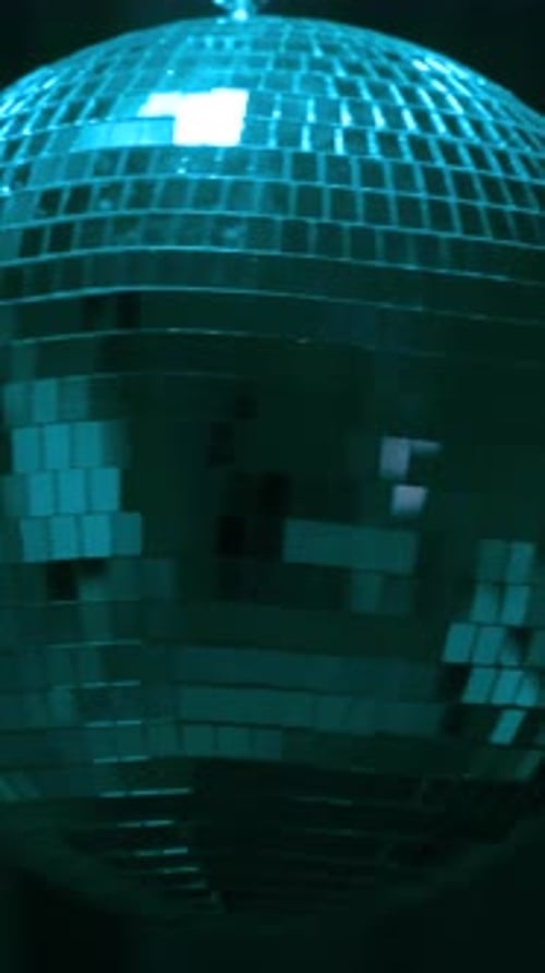 Disco ball reflects vibrant green lights. Vertical
