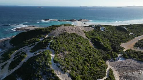 Aerial approaching shot of green coastline with rocky beach at Wylie Bay, Australia.