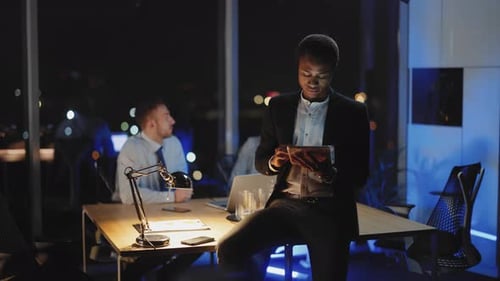 African American Empoloyee Leaning on Board Table Using Tablet Computer Communicating with Customers