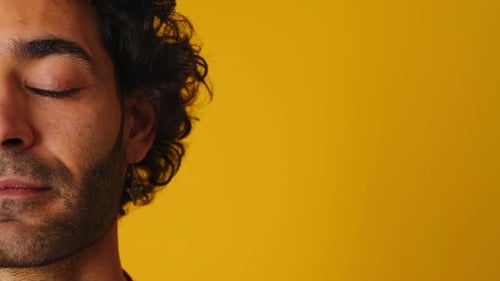 Detailed portrait of half man's face opens his eyes isolated on yellow background in studio
