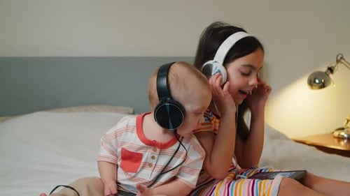 Infant and Child Enjoying Phones with Headphones Indoors