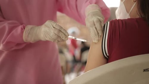 Girl Received Second Dose Of COVID-19 Vaccine By A Health Worker In PPE. - close up