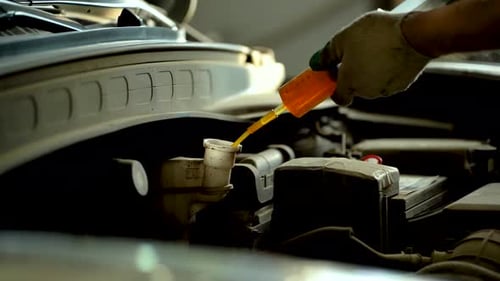 A Car Mechanic Extracts Used Brake Fluid Using a Syringe at a Service Center