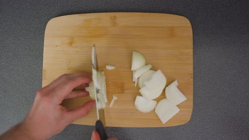 Hands Chopping Onion on Wooden Cutting Board