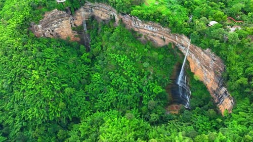 Drone captures majestic waterfall cascading from cliff.