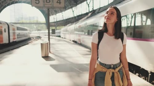 Young woman walk along the platform of the railway station in her hands with mobile phone