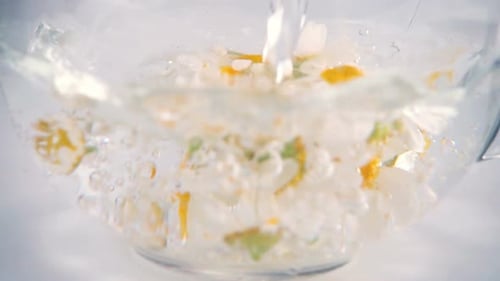 Water Pouring Into Bowl with Fresh Chamomile Flowers