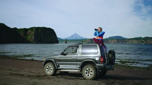 Adventurous Woman Observes Coastal Scenery with Binoculars