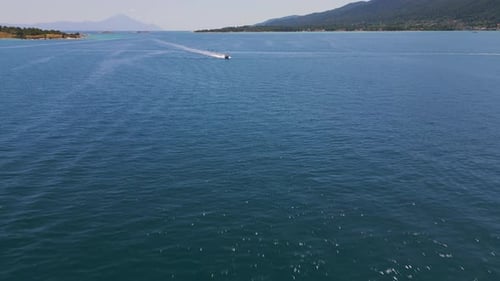 Aerial View of a Speedboat Gliding Across Sparkling Blue Sea Leaving a White Wake Behind Captures