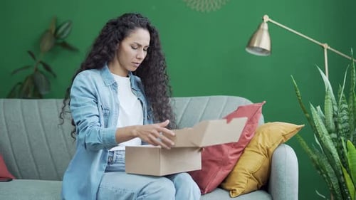 Young dark haired woman received a parcel dissatisfied with shopping in online internet store sit