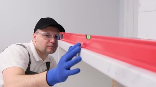 Man Using Red Level in Indoor Setting