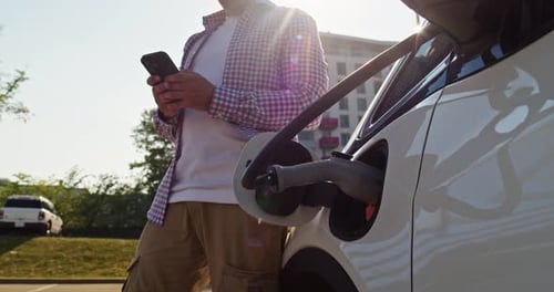 Man Driver Waits for an Electric Car to Refuel at an Electric Gas Station