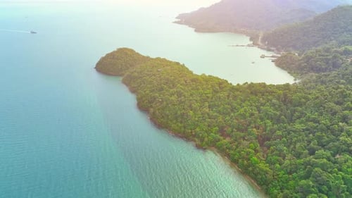 Aerial view reveals lush coastal and mountains on tropical island. 4K.