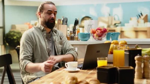 Man with Beard Talking on Laptop in Kitchen