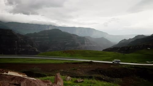 A White Minibus is Driving Along a Beautiful Mountain Road