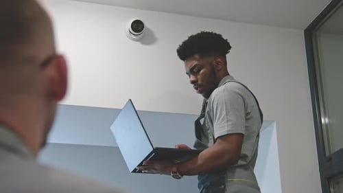 Technician Installs Security Camera With Supervisor On Site