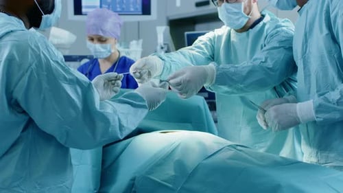 Diverse Team of Professional Surgeons Performing Invasive Surgery on a Patient in the Hospital Oper