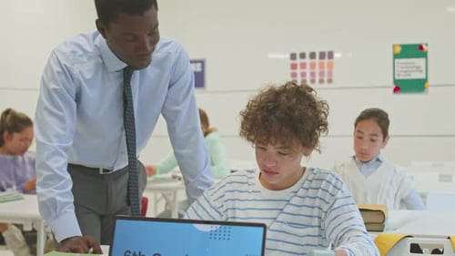 Teacher Helping a Teenaged Student in Classroom