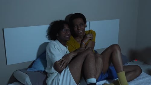 Couple Laughing Together on a Bed at Night
