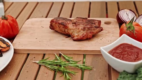 The Cook's Hands with Metal Tongs Carefully Place the Steak on a Wooden Board