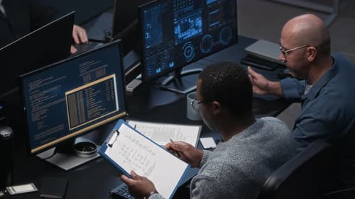 Zwei verschiedene Cybersicherheitsmitarbeiter analysieren Dokumente und überwachen Daten