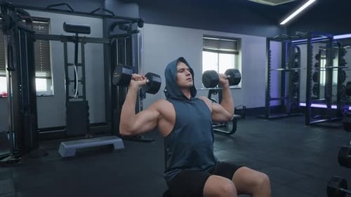 Muskulöser Mann trainiert Hantel-Schulterpresse im Fitnessstudio