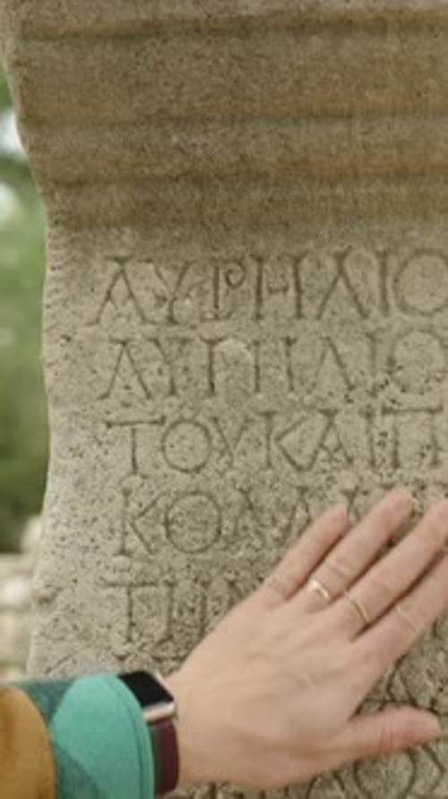 Hand Touches Stone with Ancient Writing