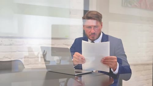 Man Working With Laptop And Papers In Office