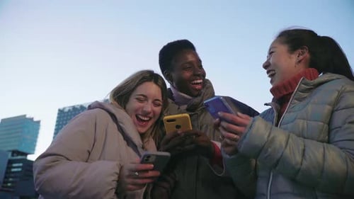 Friends Laughing Using Phones in the City