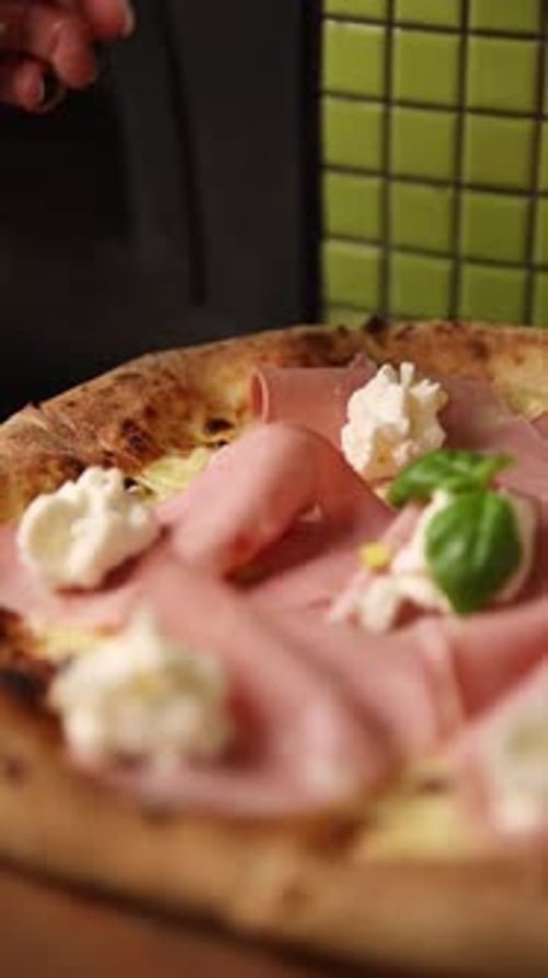 Close-up Adding Basil to a Pizza with Mortadella