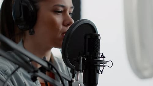 Woman Speaking into Microphone in Home Studio
