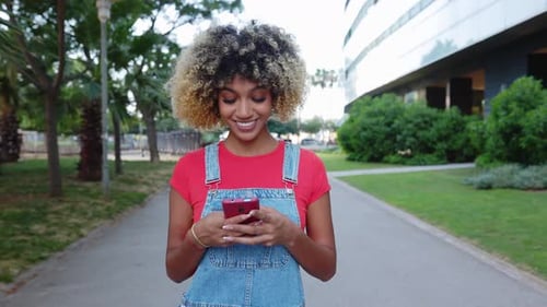 Woman Using Phone on a City Sidewalk