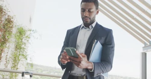 Happy african american businessman using smartphone and celebrating at office, slow motion